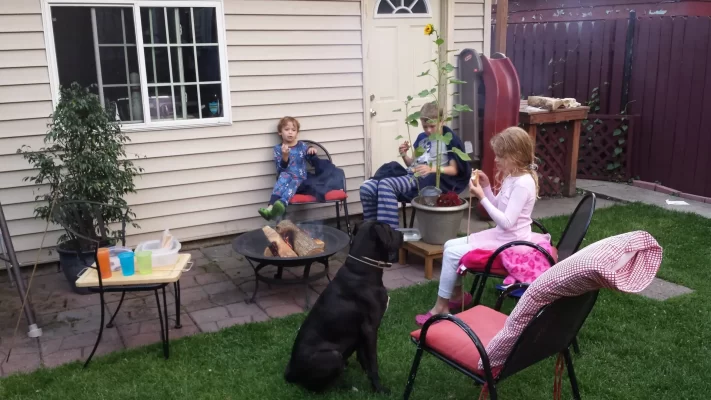 Young children enjoying s'mores in the backyard on a warm summer night