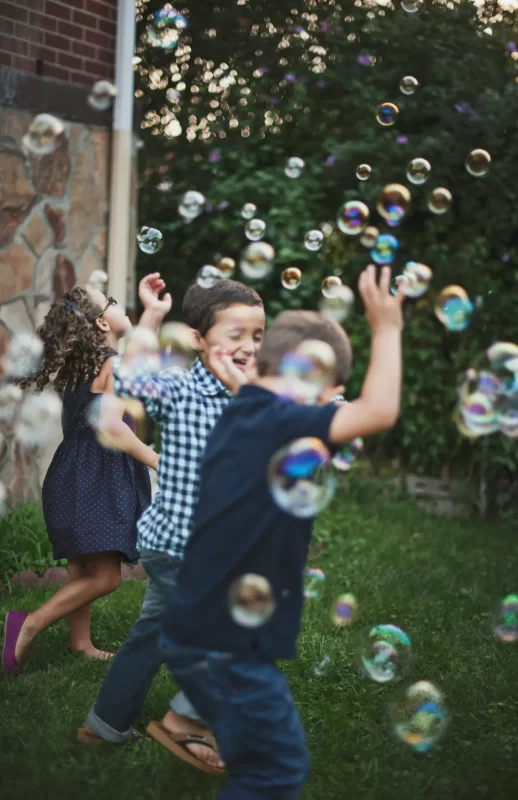 Kids having fun in the backyard playing with Bubbles laughing and running