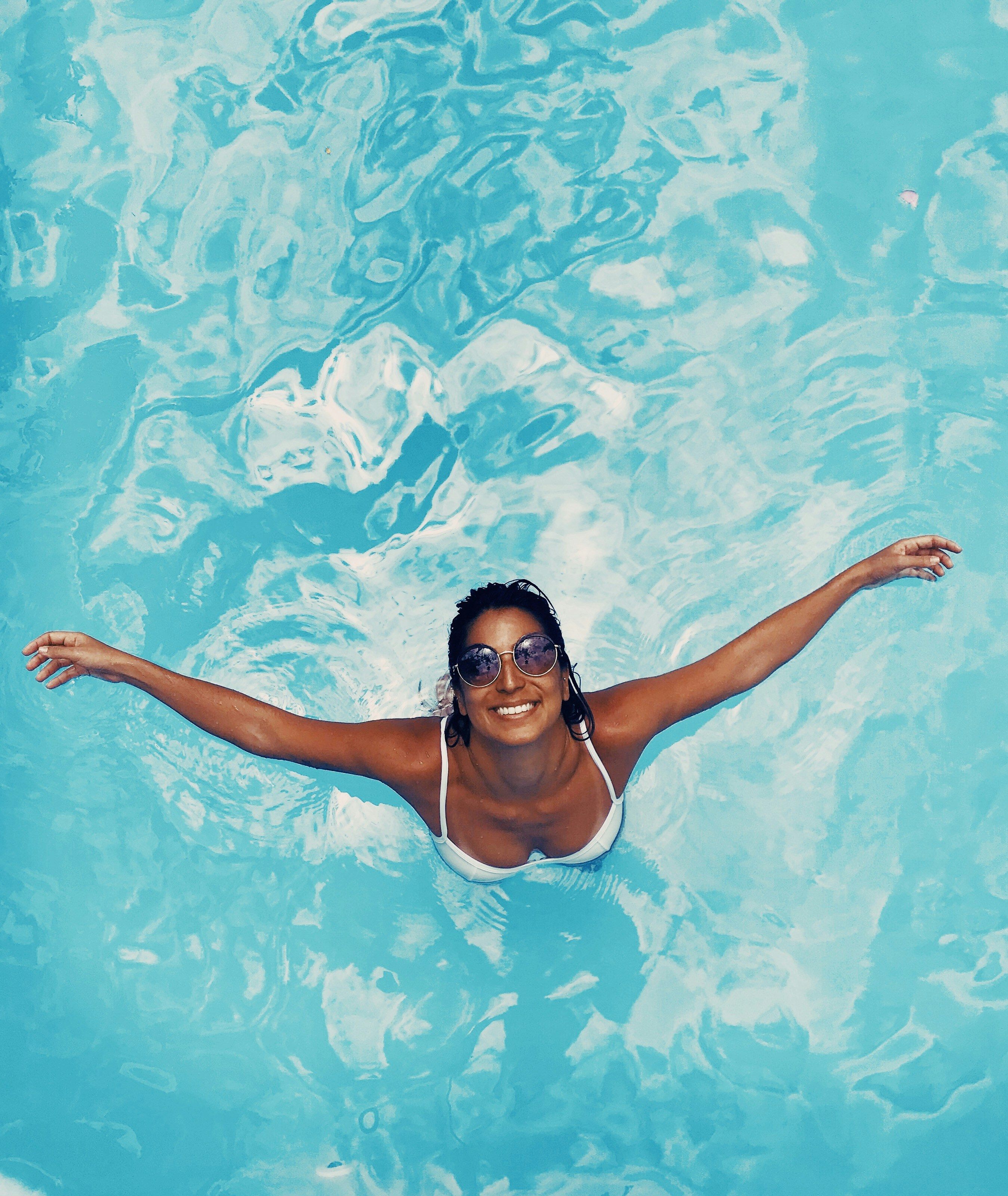 Woman splashing happily in pool on a warm summer day