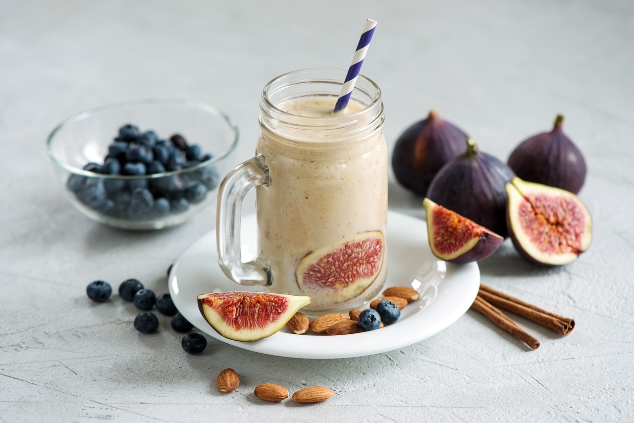 Healthy Protein shake in glass jar sitting on a table surrounded by blueberries and figs