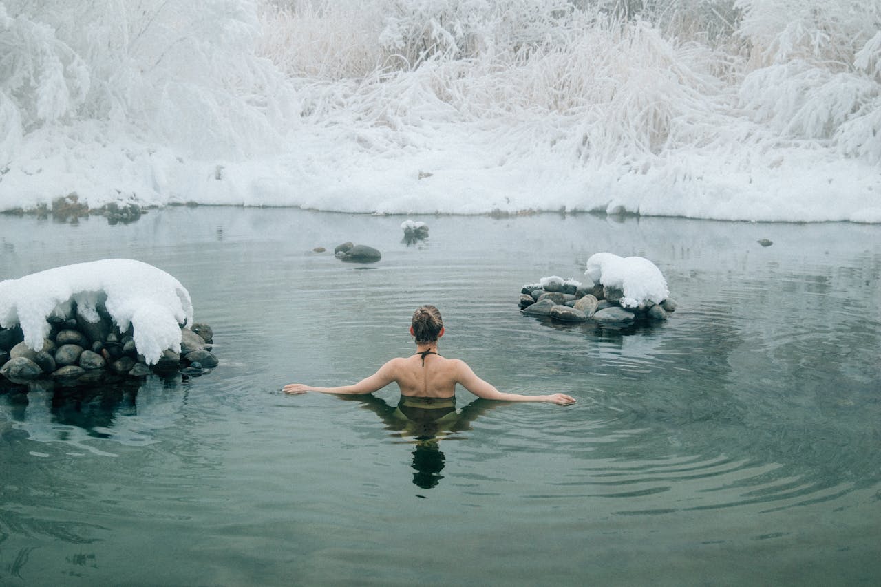 woman immersed in lake during winter surrounded by snow
