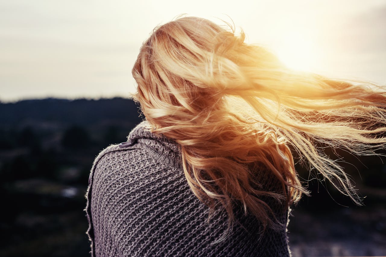 Woman with long healthy hair standing on a hill looking at the sunset in the fall