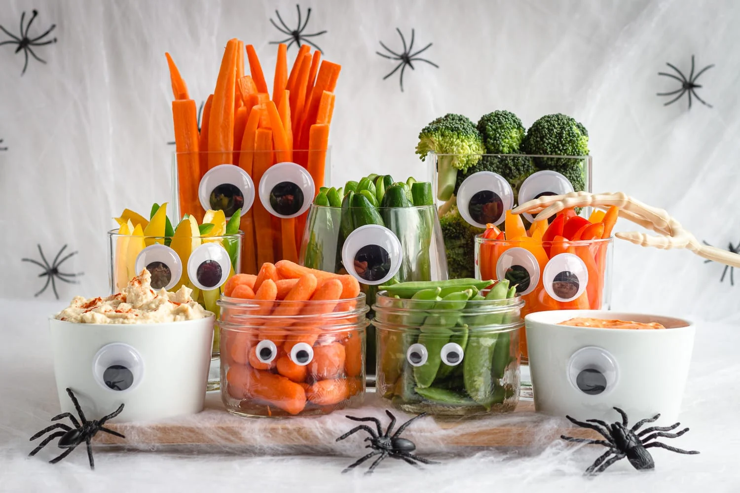 veggies cut up and placed in clear plastic cups decorated with Halloween eye candy
