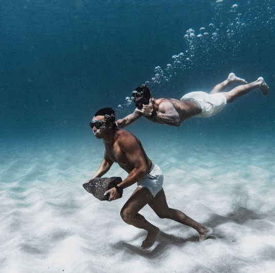 Two athletes under water running with weights exercising
