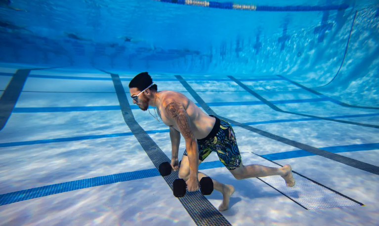 Under water fitness used by a man carrying weights under water for exercise